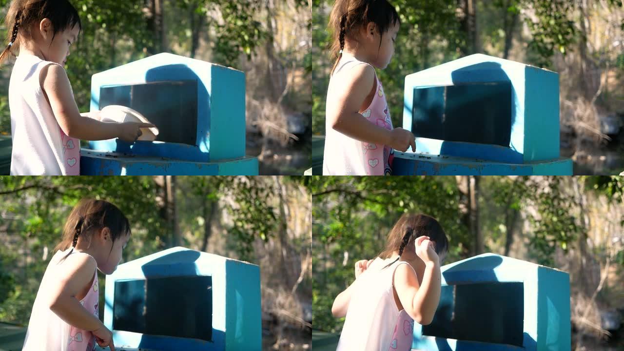 可爱的小女孩在公园的回收箱里扔塑料食品容器。拯救世界的概念。零浪费。