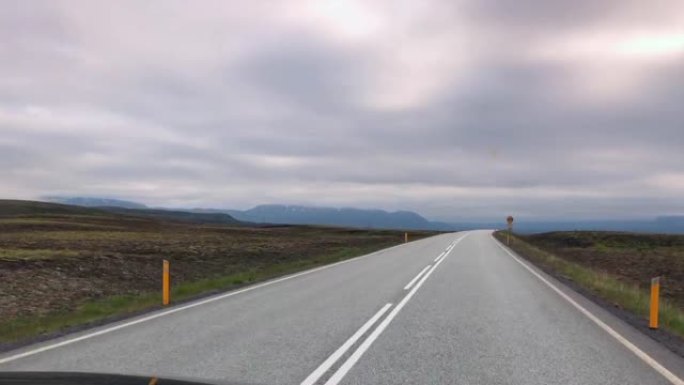 汽车在冰岛的道路上行驶。从车内看道路。冰岛美丽的自然，广阔的空间，山脉，空旷的长路。