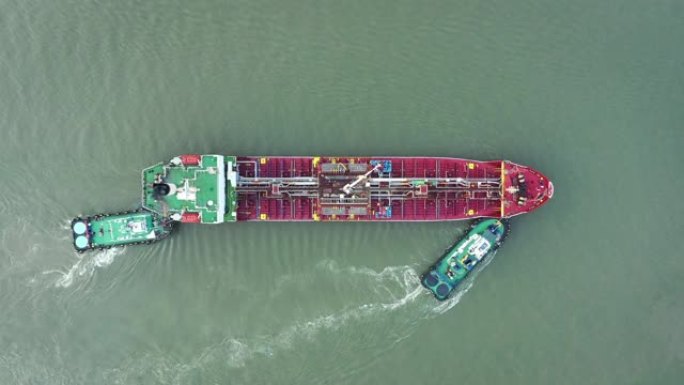 空中俯视图拖船将油轮推到装货码头，以从炼油厂装载或卸载石油，以进行运输或能源概念背景。