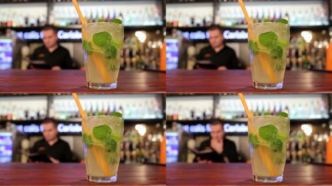 酒吧台特写镜头上的玻璃杯和冰块中的新鲜莫吉托鸡尾酒。在夜总会用酸橙和薄荷叶，冷水晶喝酒精饮料