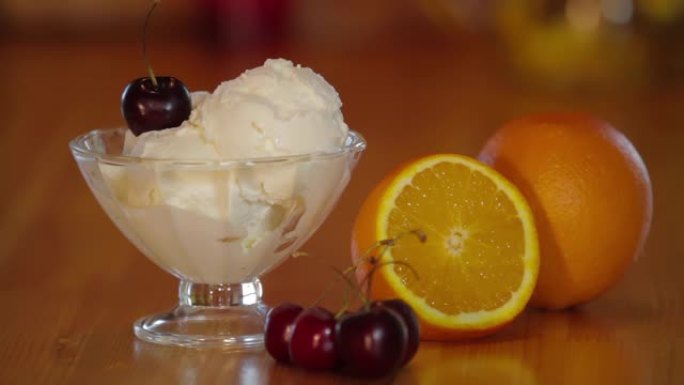 冰淇淋勺上的樱桃。冰激凌，玻璃碗里有樱桃，木桌上有橙色。冰淇淋冰淇淋的制备。甜冷甜点。