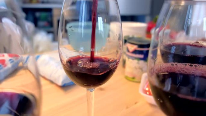 红酒被倒入家里厨房的酒杯中。