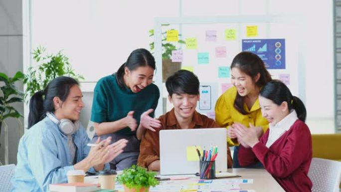 商业上的成功，一群快乐的亚洲创意商业团队为在会议室办公室赢得项目而鼓掌庆祝