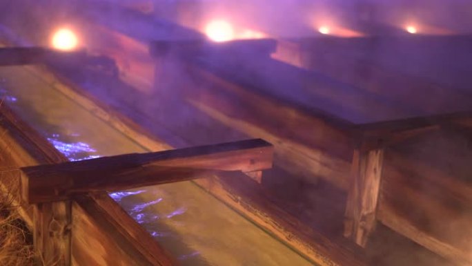 在寒冷的冬夜，蒸汽上升，木制滑道在草津温泉镇的镜头。日本文化、旅游和生活方式。