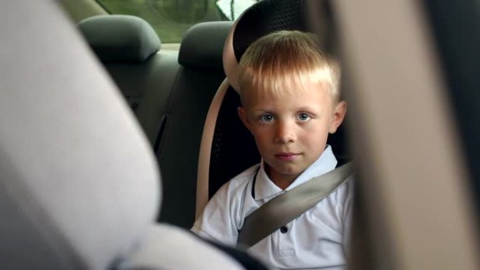 在夏季旅行中，一个男孩坐在儿童汽车座椅上的肖像，特写镜头。