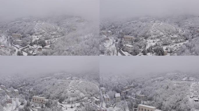 在白雪皑皑的小镇Tkibuli上空的云层中飞行，在佐治亚州的国家拍摄，无人机4K