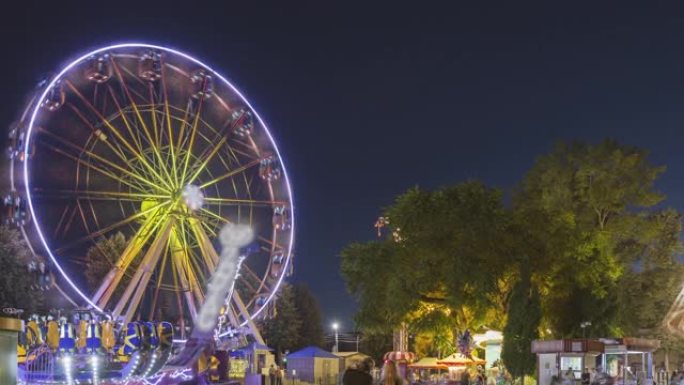 在城市游乐园的夏日夜晚，运动中的旋转照亮了吸引人的摩天轮和明亮的旋转木马。