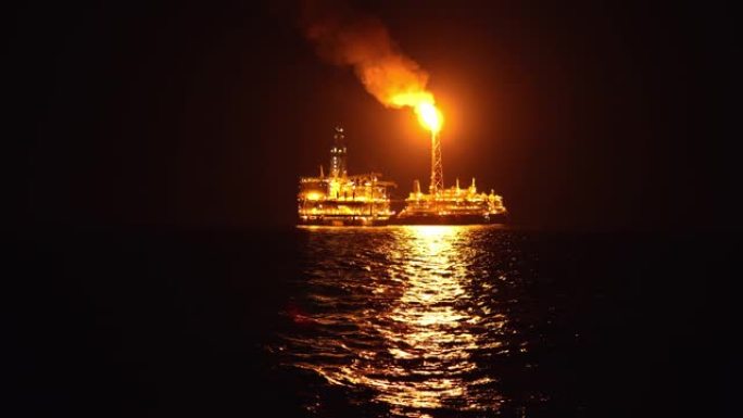FPSO油轮在夜间靠近石油平台钻机。海上石油和天然气工业