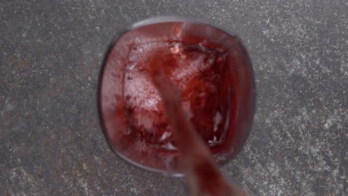 葡萄汁倒入玻璃中的俯视图，背景浅。桌上新鲜的红色饮料鸡尾酒杯