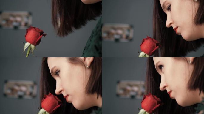 红玫瑰女孩若有所思地嗅着美丽的花朵。情人节，2月14日，生日，周年纪念日，第一次约会概念。侧视图。慢