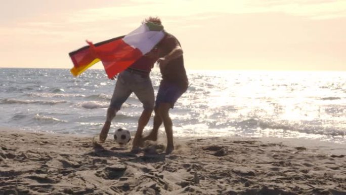 日落时，两名戴着意大利和德国国旗的年轻人在海边的海滩上踢足球