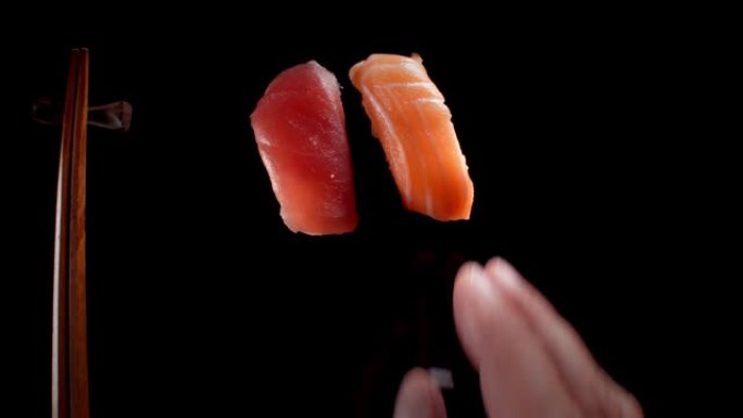 用手和筷子在黑暗的极简主义工作室场景中供应寿司