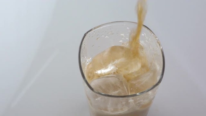 冷清爽的可乐倒入白色背景上带有冰的玻璃杯中，并留有文字空间。冰凉饮料含咖啡因