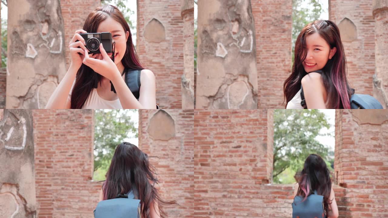 美丽的亚洲年轻女性用胶片相机拍照。她正在世界遗产城市大城府散步。概念自由女人玩得开心，度假旅行。慢动