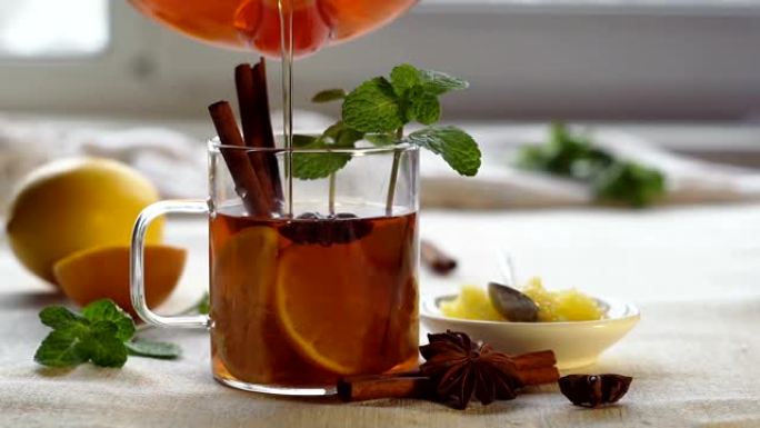 将茶壶中的热茶倒入装有柠檬，肉桂和薄荷的杯子中