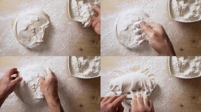 慢动作俯视图，男人的手在家里用书折叠技术在轻薄的木板上用白面粉处理比萨饼面团时，用手将面粉撒在比萨饼
