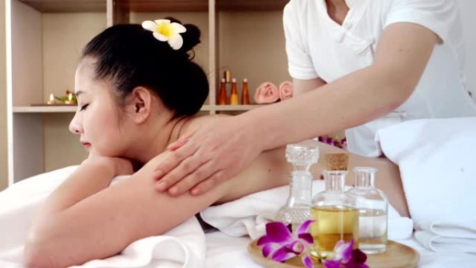 亚洲女性放松，同时接受专业按摩师的美容和健康按摩。按摩师用油按摩亚洲女性的身体