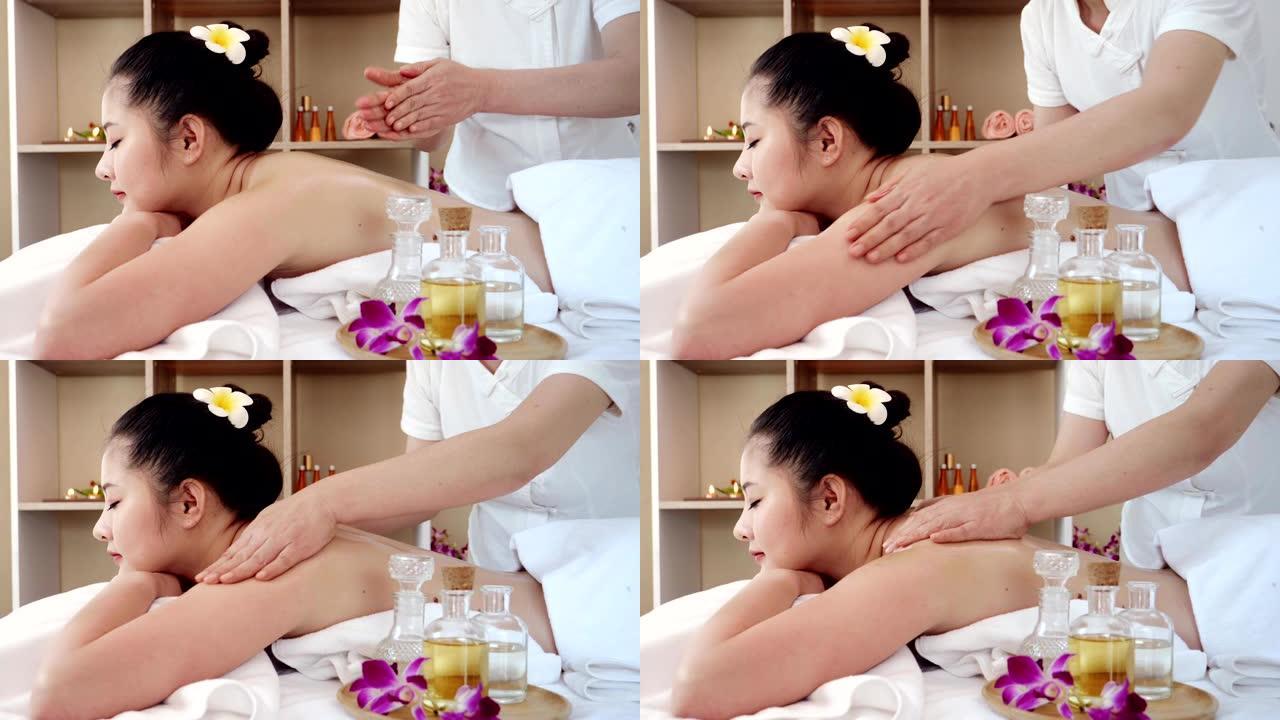 亚洲女性放松，同时接受专业按摩师的美容和健康按摩。按摩师用油按摩亚洲女性的身体