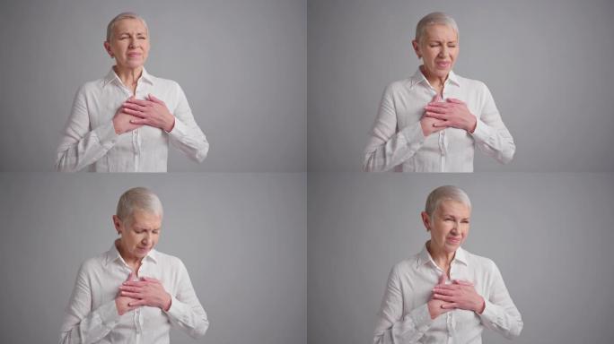 老年妇女在灰色背景上心脏病发作。老年妇女有胸痛