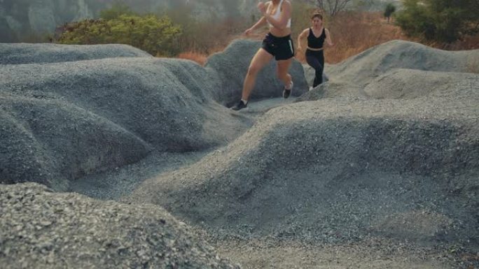 慢动作，在岩石山上跑步的伙伴爬上去，运动员适合两名女性运动跑步者在美丽的大自然中专业户外艰难而富有挑