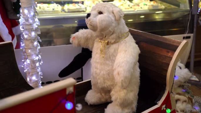 美丽蓬松的白色泰迪熊在木制雪橇上，当地酒吧有圣诞装饰。令人惊叹的儿童机械移动玩具，泰迪熊展示圣诞节假