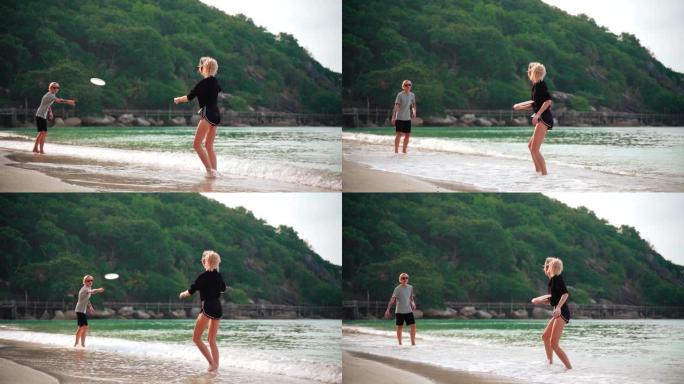 晴天，两个年轻女子在热带海滩扔飞盘。