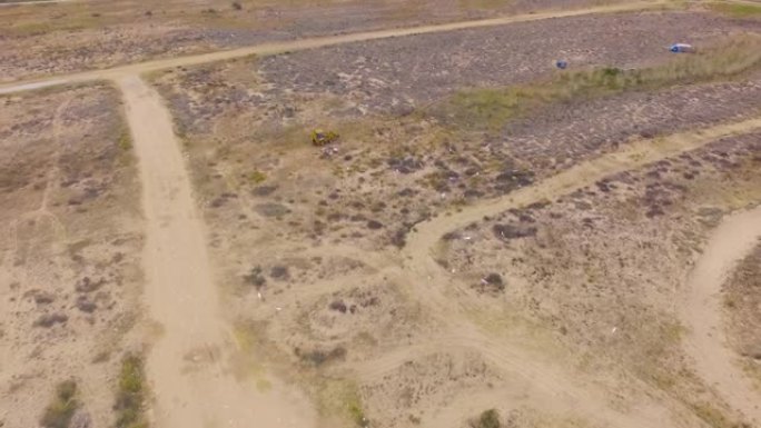 黄色挖掘机驶过沙质地形。空中无人机镜头