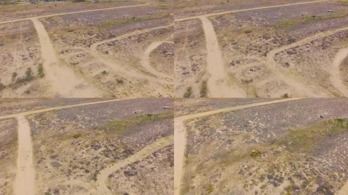 黄色挖掘机驶过沙质地形。空中无人机镜头