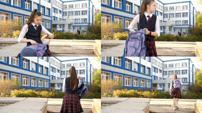 在学院院子里休息的十几岁的女孩带着背包坐在栏杆上，在智能手表上设置闹钟。
