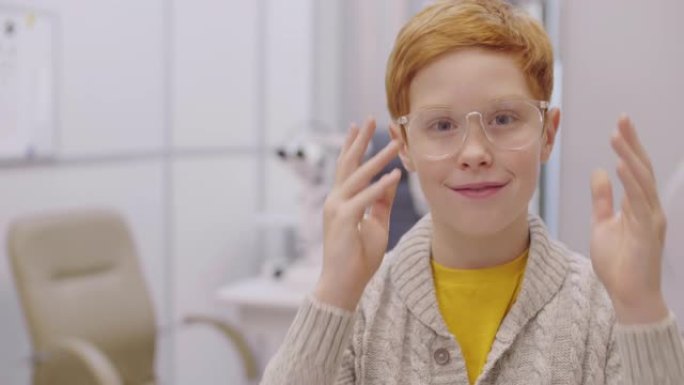 戴着眼镜的快乐红发男孩在眼科诊所为相机摆姿势