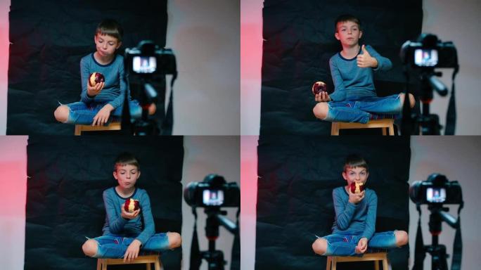 一个男孩正在摄像机前吃一个红苹果。