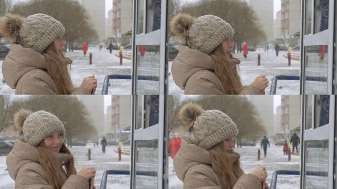 少年女孩在冬季散步时在街头售货亭挑选商品。微笑的女孩买家拿着钱钱包前街商店在下雪的冬天散步。