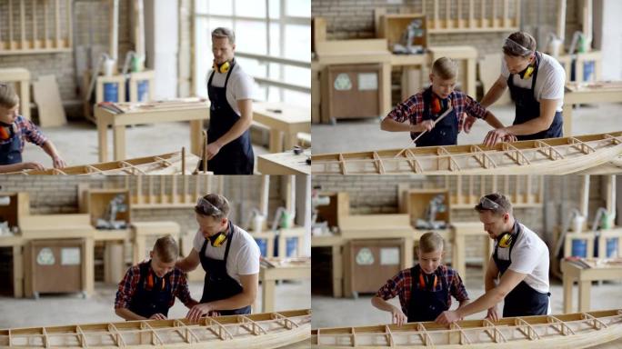 中年木匠走向工作台并鼓励小儿子在木工店里建造大型木船模型的跟踪镜头