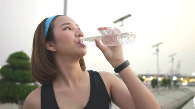 亚洲女子日落跑步后慢跑锻炼喝水