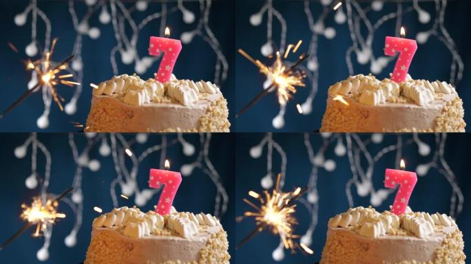生日蛋糕，7号粉色蜡烛和蓝色背景上的烟火。慢动作和特写视图