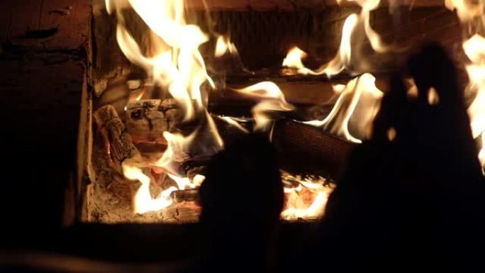 这对夫妇在温暖的炉火旁放松，温暖着他们裸露的双腿。
