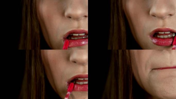 艺术家的手化妆，画出女孩的嘴唇特写。骨头用红色唇膏涂她的嘴唇。在时尚美容行业工作的模特