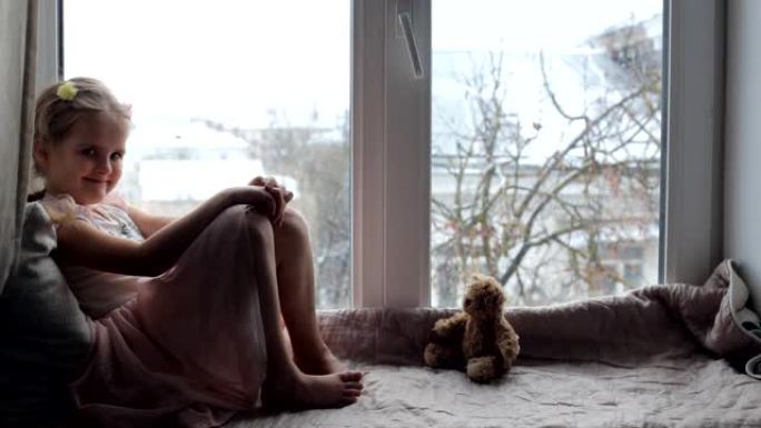 女孩坐在窗台上，带着泰迪熊，微笑着