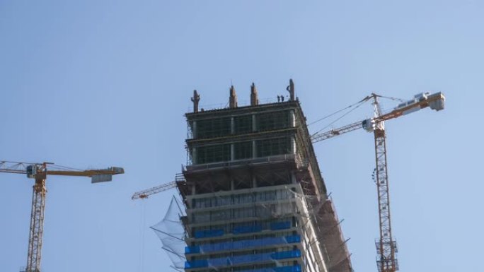 建筑工地上的塔式起重机在高层建筑中举起负载。延时
