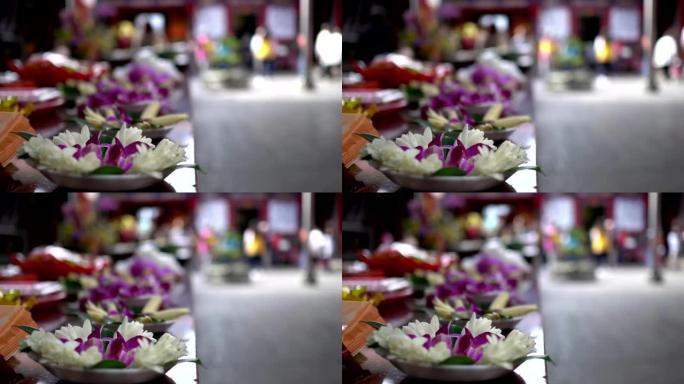 亚洲寺庙祭祀用的花。模糊的背景是朝拜者经过。主题在左边。