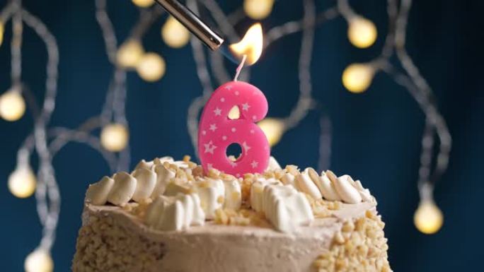 蓝色背景上有6个数字粉色蜡烛的生日蛋糕。蜡烛着火了。慢动作和特写视图