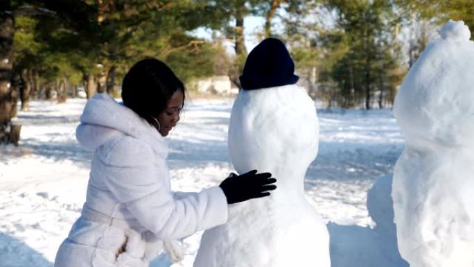 非裔美国妇女在冬季大自然中堆雪人