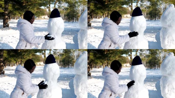 非裔美国妇女在冬季大自然中堆雪人