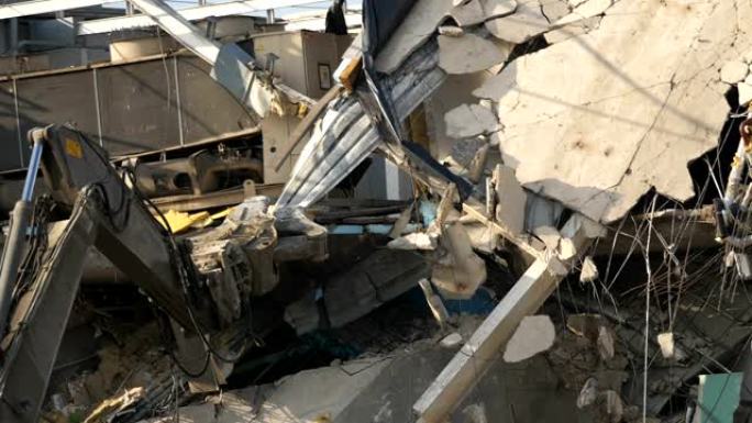 建筑物拆除。一个巨大的机器手臂摧毁了房子。灰尘、碎片、砖块、碎片飞下来。
