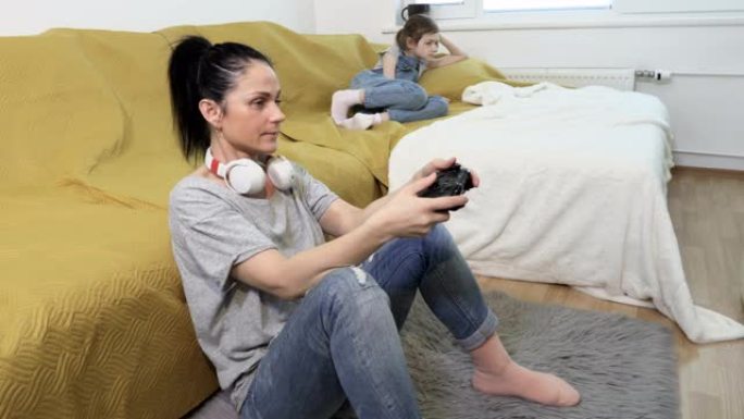 心烦意乱的女儿很生气，因为她的母亲在沙发附近的家里玩电子游戏