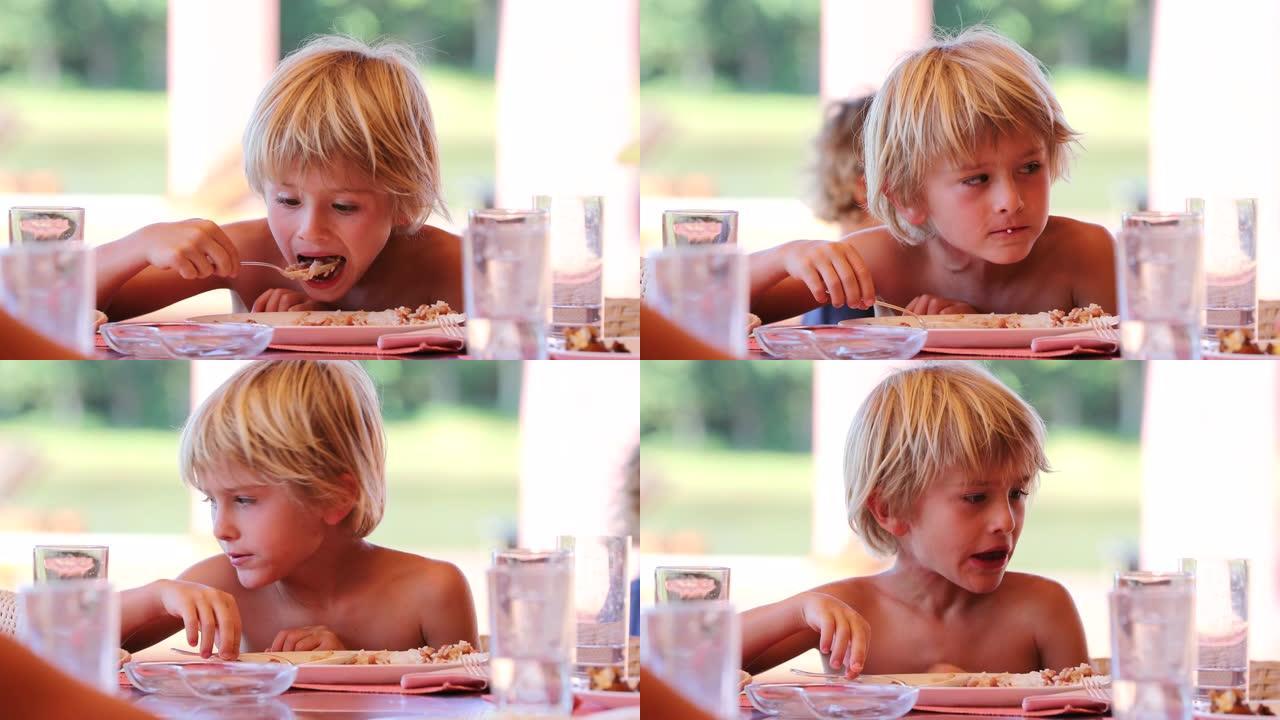 坦率的年轻金发男孩在午餐时和家人一起在户外休闲吃饭