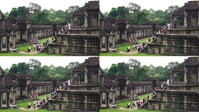 在吴哥窟寺庙废墟中行走的游客。树木生长在建筑物中。联合国教科文组织历史遗址。著名的旅游目的地为背包客