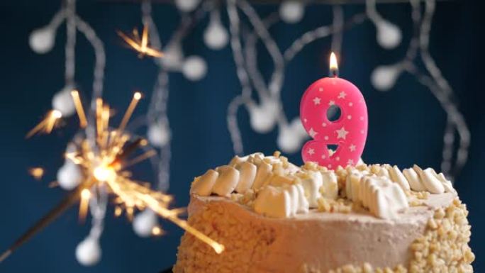 生日蛋糕，蓝色背景上有9号粉色蜡烛和烟火。慢动作和特写视图