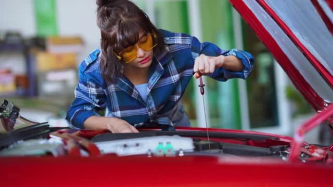 年轻的女技术员检查车库中的机油