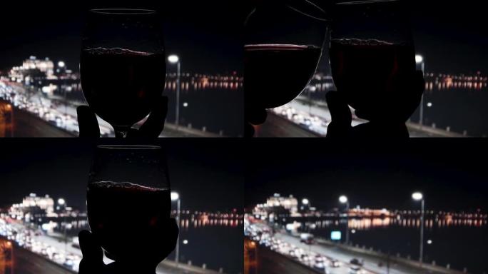 在散焦的黑暗背景上在玻璃杯中挥舞红酒。夜城生活美丽的葡萄酒广告素材。